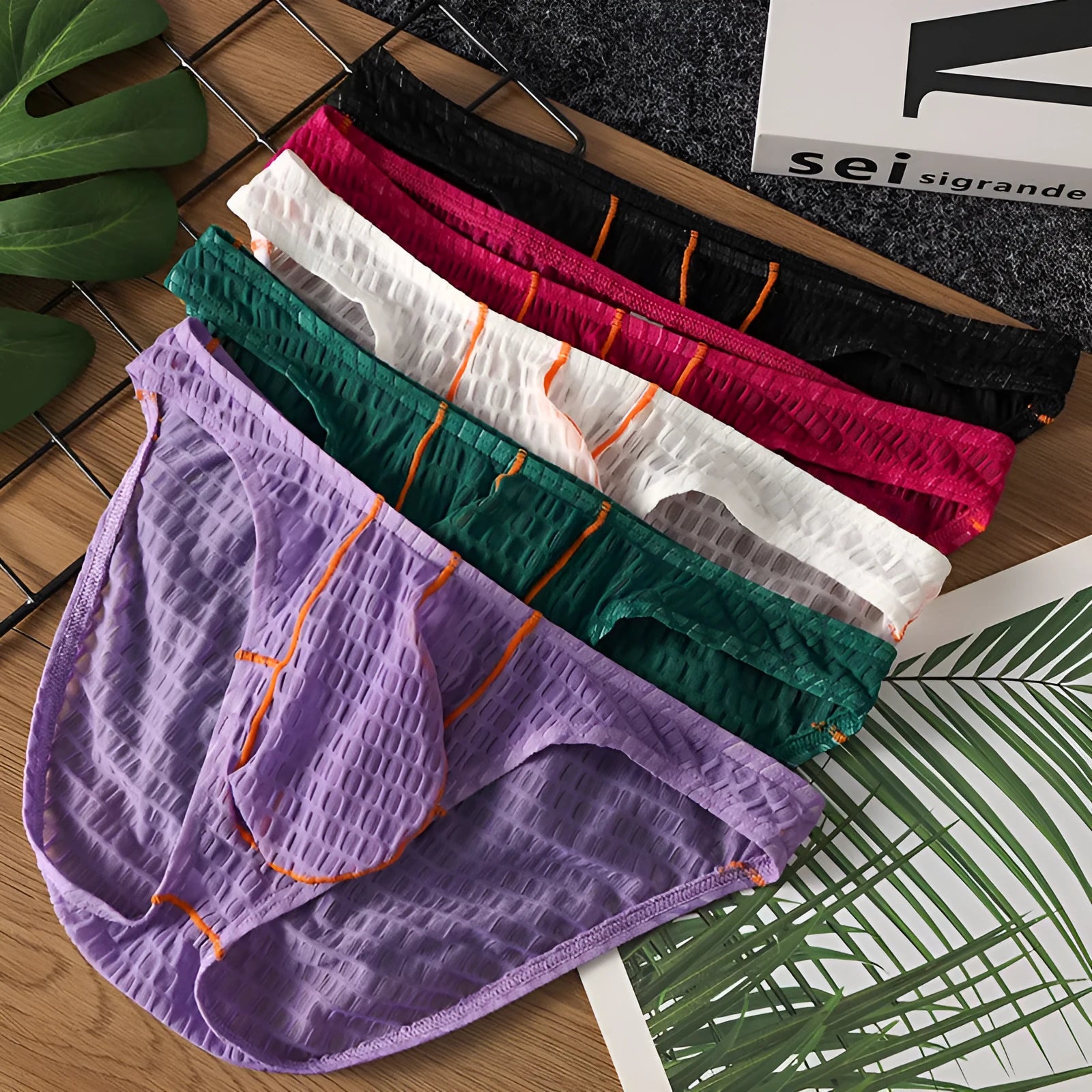 Men's low waist lace briefs in ice silk fabric on solid colour background