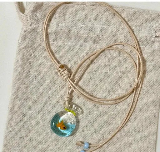 Women's necklace with small coloured glaze fish lucky bag pendant on a braided cotton and linen chain.