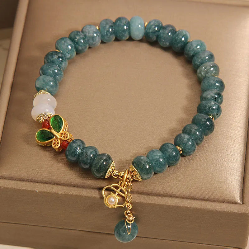 Close-up of a women's bracelet with blue water jade abacus beads, white agate, alloy inlay, and a butterfly clasp.