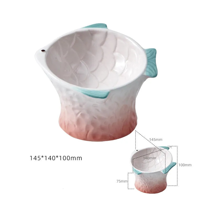 Four coloured fish-shaped ceramic cat bowls with tilted bases on a table.