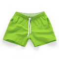 Men's plus size polyester surf shorts on a beach, showing straight leg fit in black and emerald green colours.