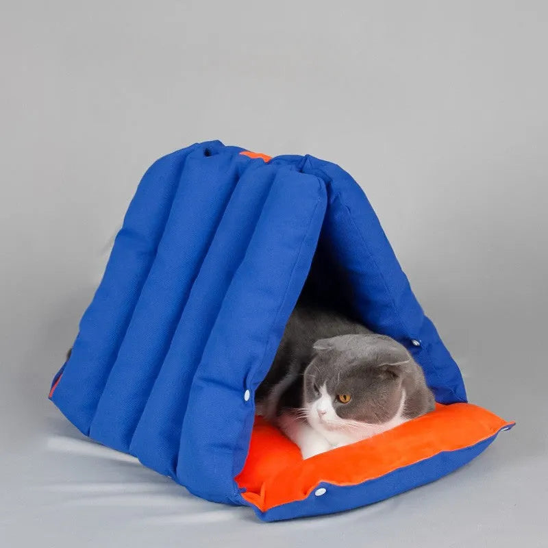 Blue triangular cat bed with drilled holes on a sofa, showing removable cotton cover.