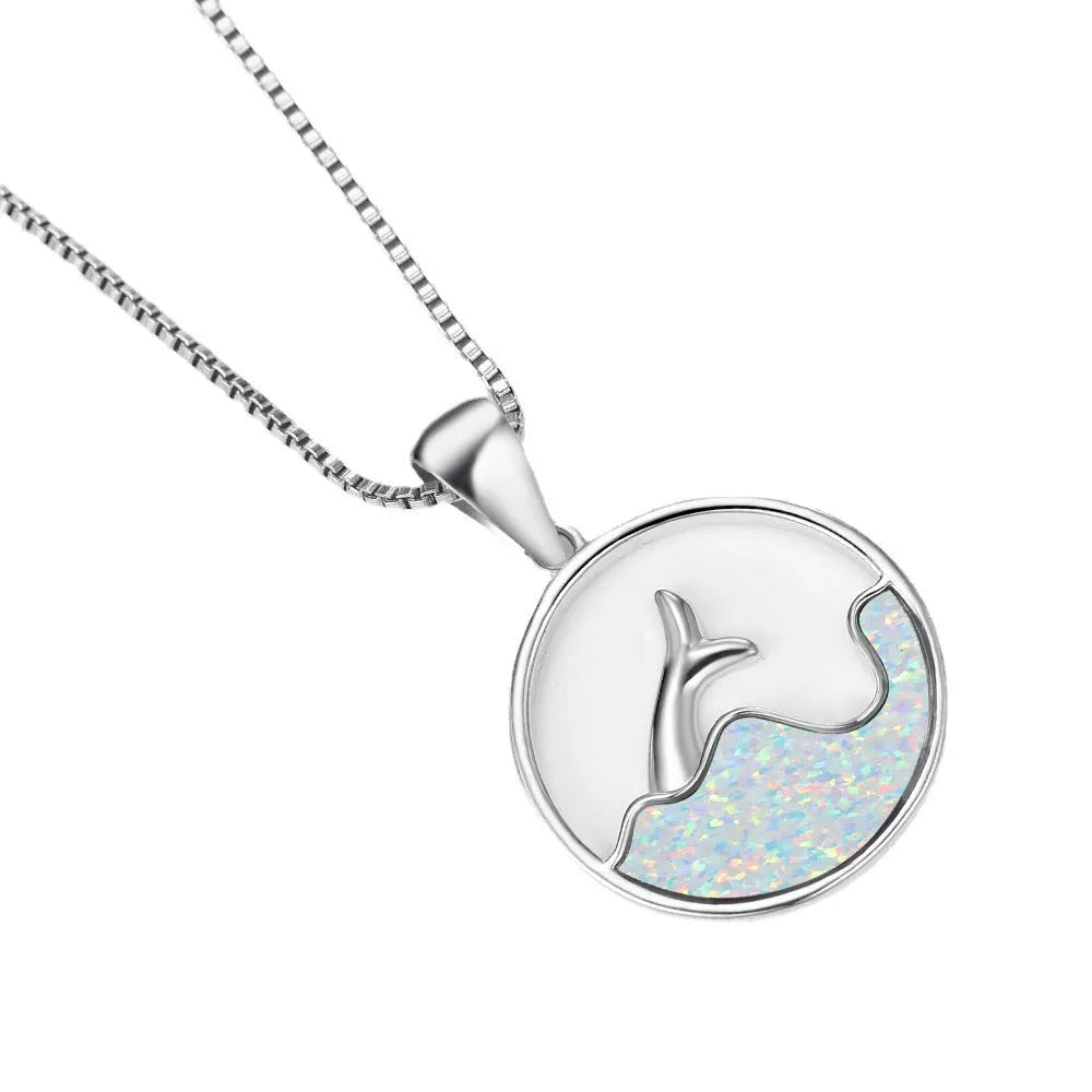 Close-up of a women's geometric fishtail necklace with a round blue opal pendant on a white gold-coloured chain.