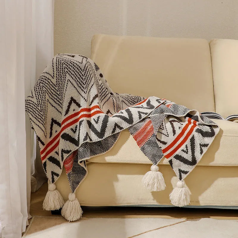 Acrylic sofa blanket with tassel fringe in neutral beige tone on grey sofa