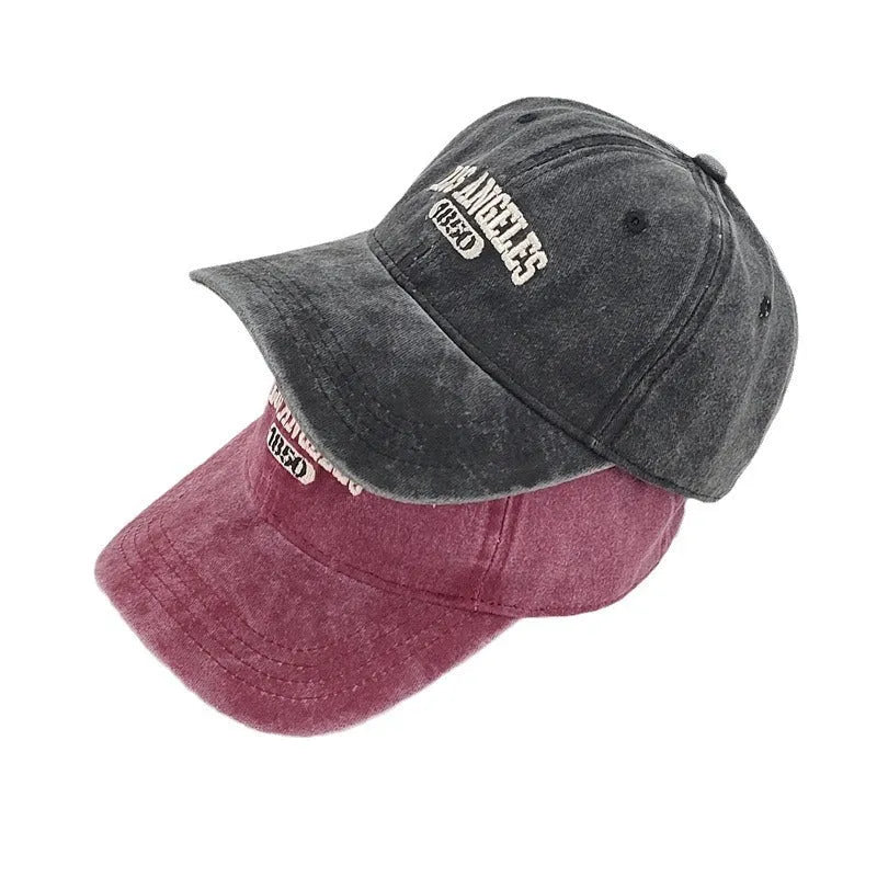Retro style peaked cap with embroidered distressed letters on the front, shown in beige colour.