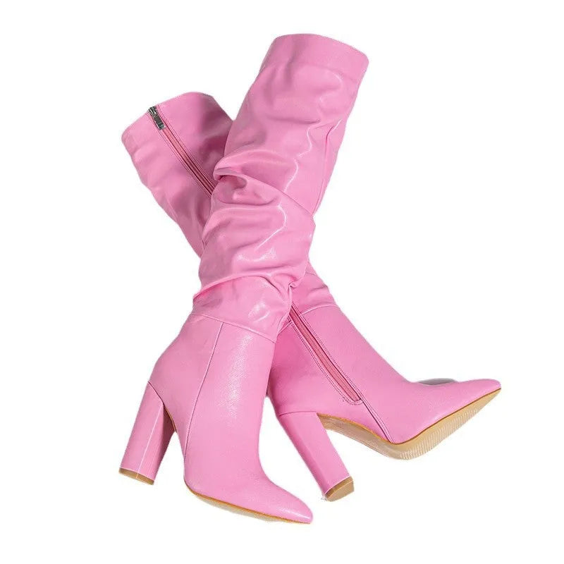 Women's white pointed toe high-heel ankle boots with side zipper on a pink background.
