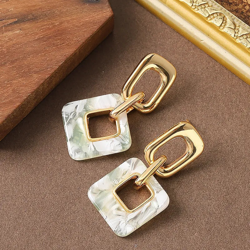 Pair of hollow square earrings with bevelled corners in a metallic finish, shown on a white background.
