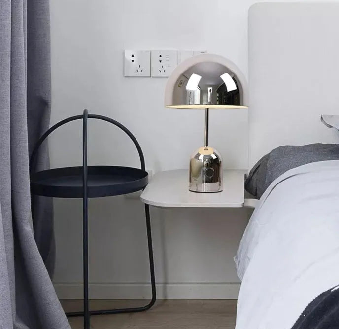 Mushroom-shaped metal table lamp in a rose gold finish on a wooden surface.