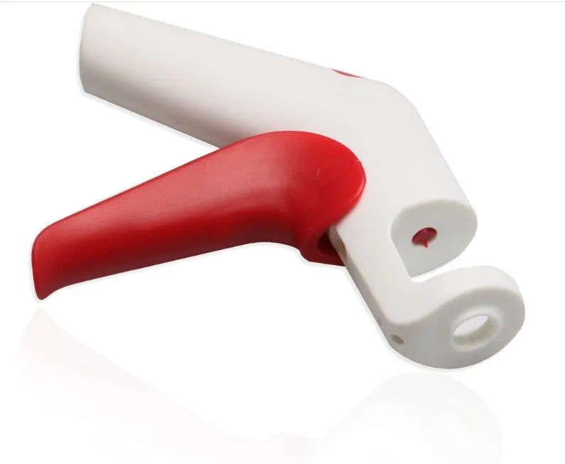 Stainless steel manual cherry kernel remover tool on a kitchen worktop.