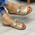 Ladies black fish mouth open-toe sandals with a gold bow detail on the strap.