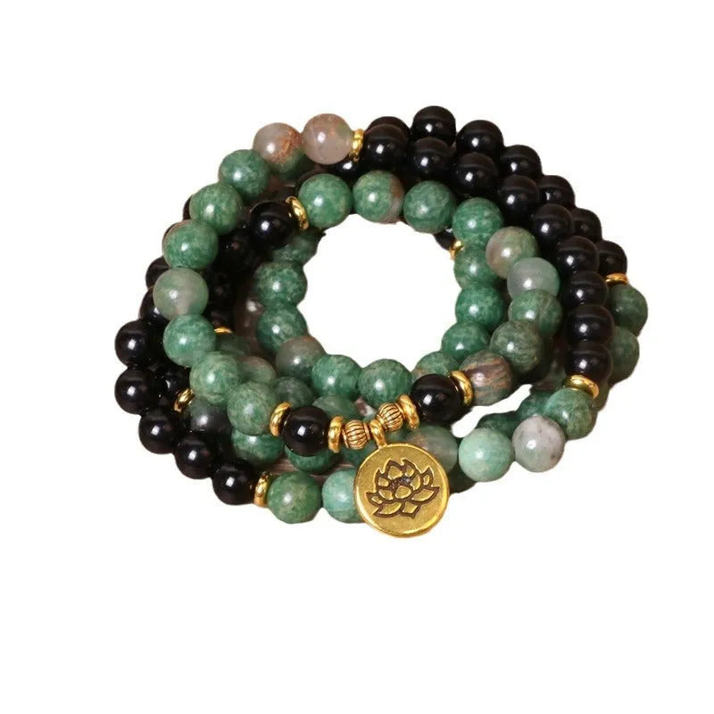 Green and black alloy bead elastic bracelet stretched on a wrist.