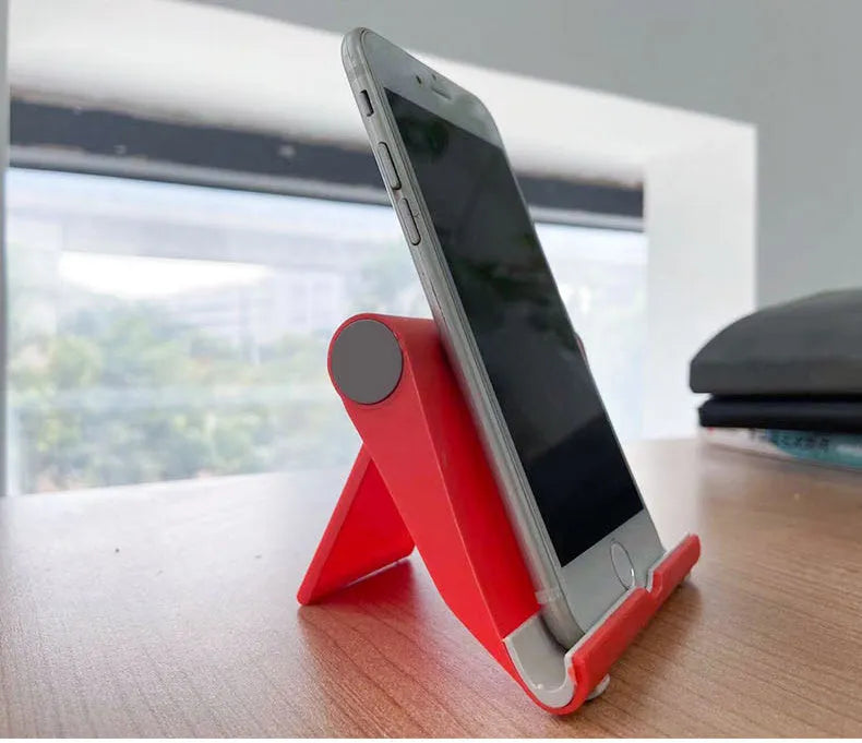 Black PE folding mobile phone and tablet stand on a wooden desktop, shown in an open, angled position.