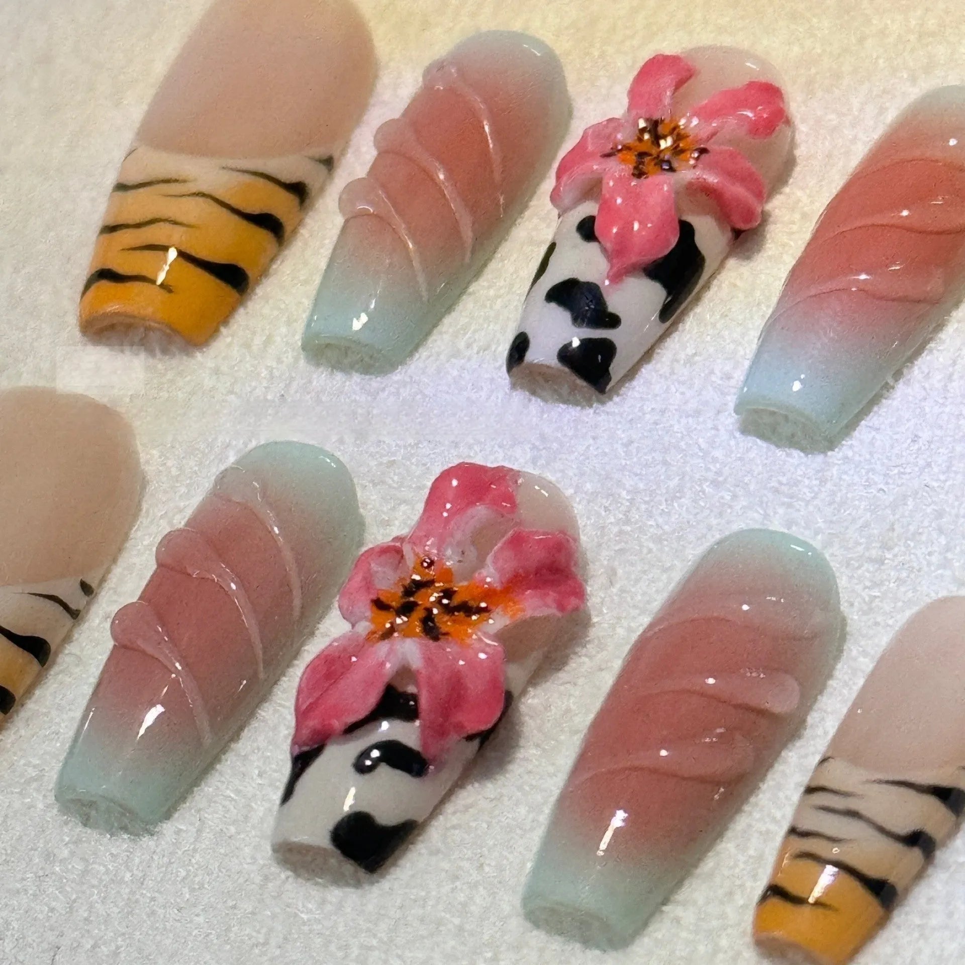 Hand-carved zebra pattern and lily design nail art pieces in four sizes on a clear background.