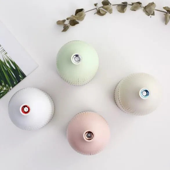 White ultrasonic aromatherapy diffuser humidifier with USB cable and LED light on wooden table