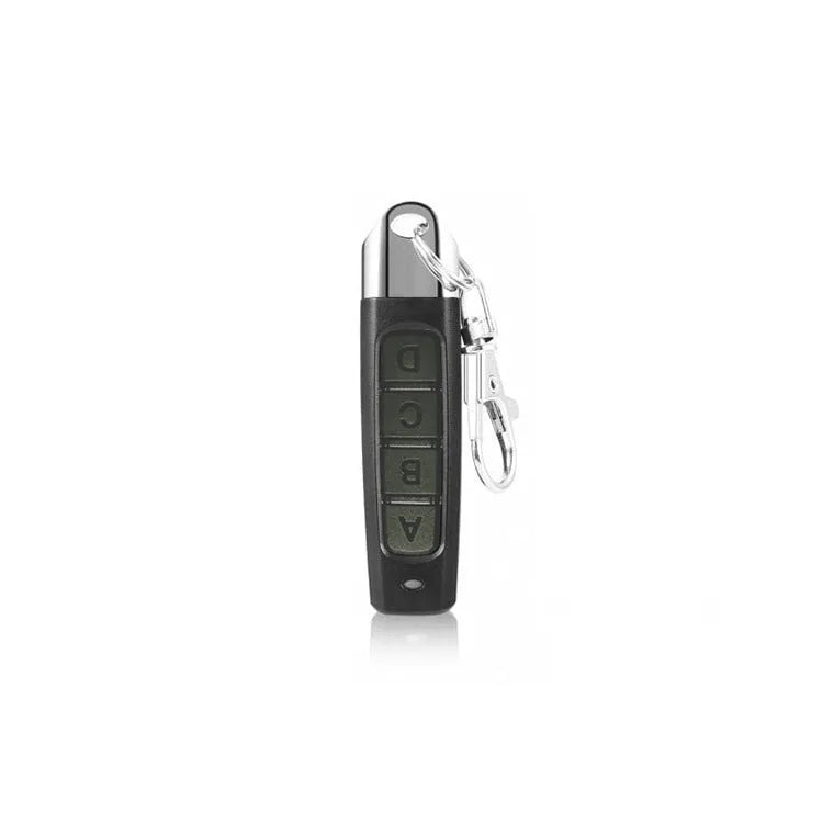 A black rolling door remote control duplicator unit showing its compact size and buttons for copy and test functions.