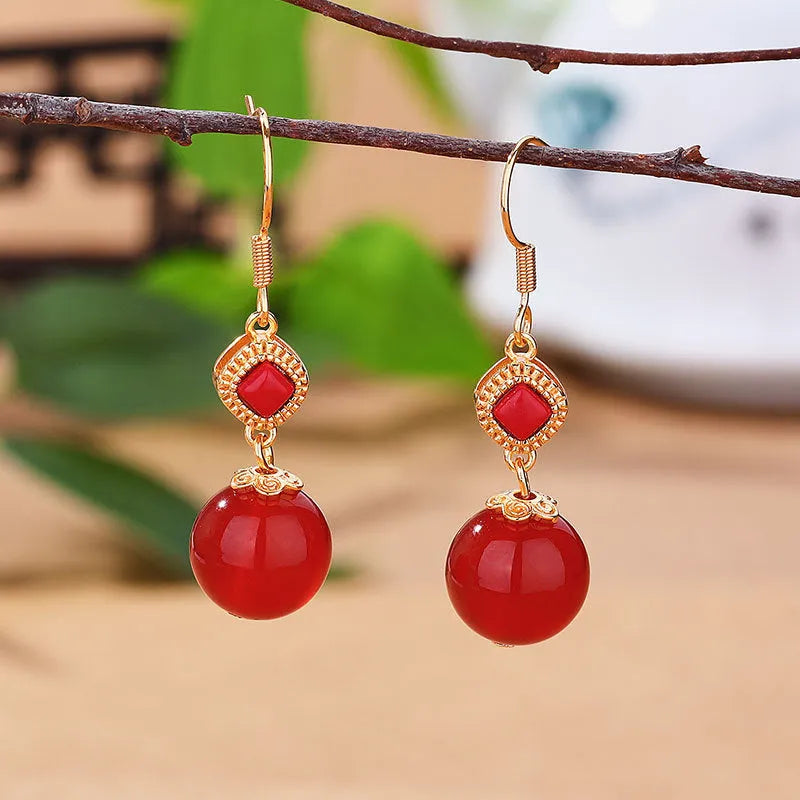 Geometric drop earrings with red agate beads, silver settings, and jasper accents on copper alloy