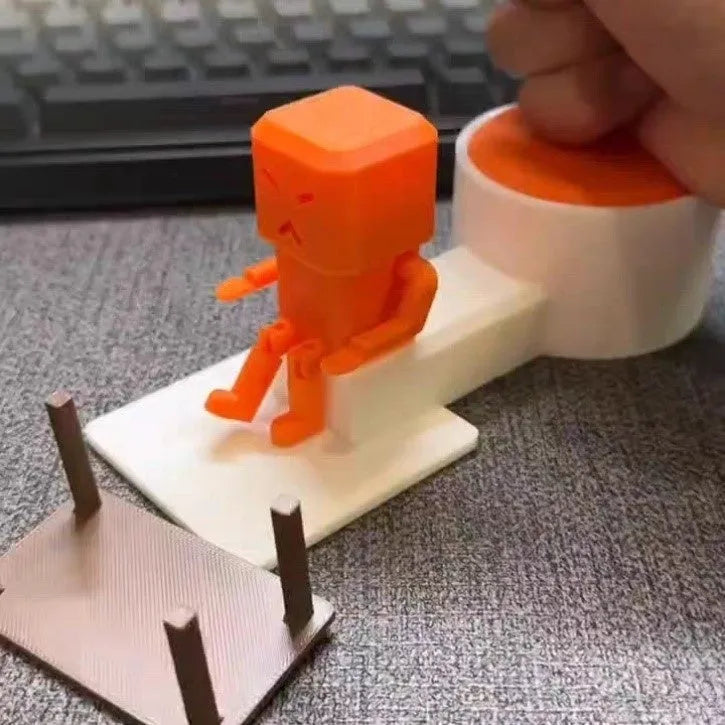 Orange plastic table-turning decompression toy measuring 16cm long on a desk