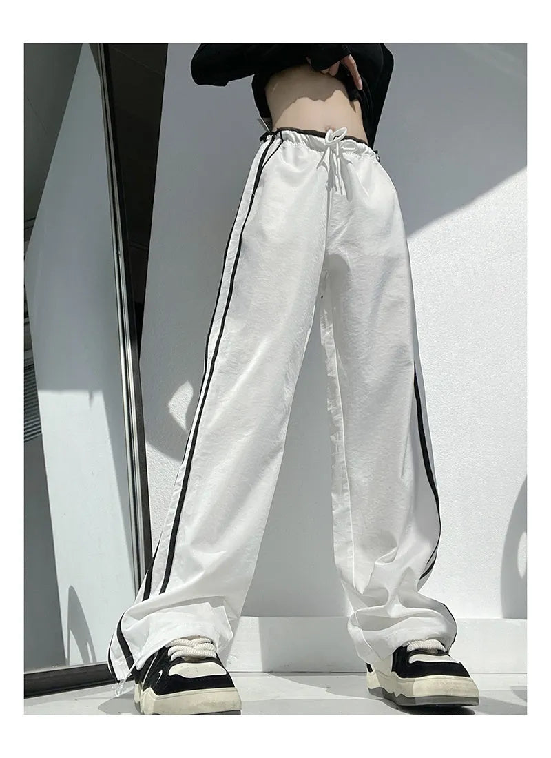 Women's navy blue loose straight-leg trousers with white contrast ribbon detail on parallel bars, low waist, draping silhouette