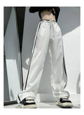 Women's navy blue loose straight-leg trousers with white contrast ribbon detail on parallel bars, low waist, draping silhouette