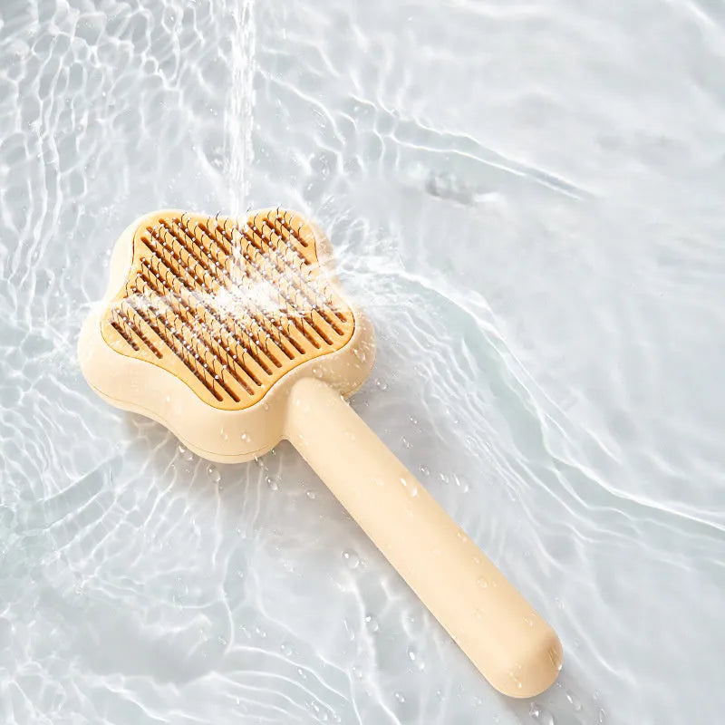Green stainless steel cat comb with magic wand self-cleaning mechanism showing needle teeth and plastic handle