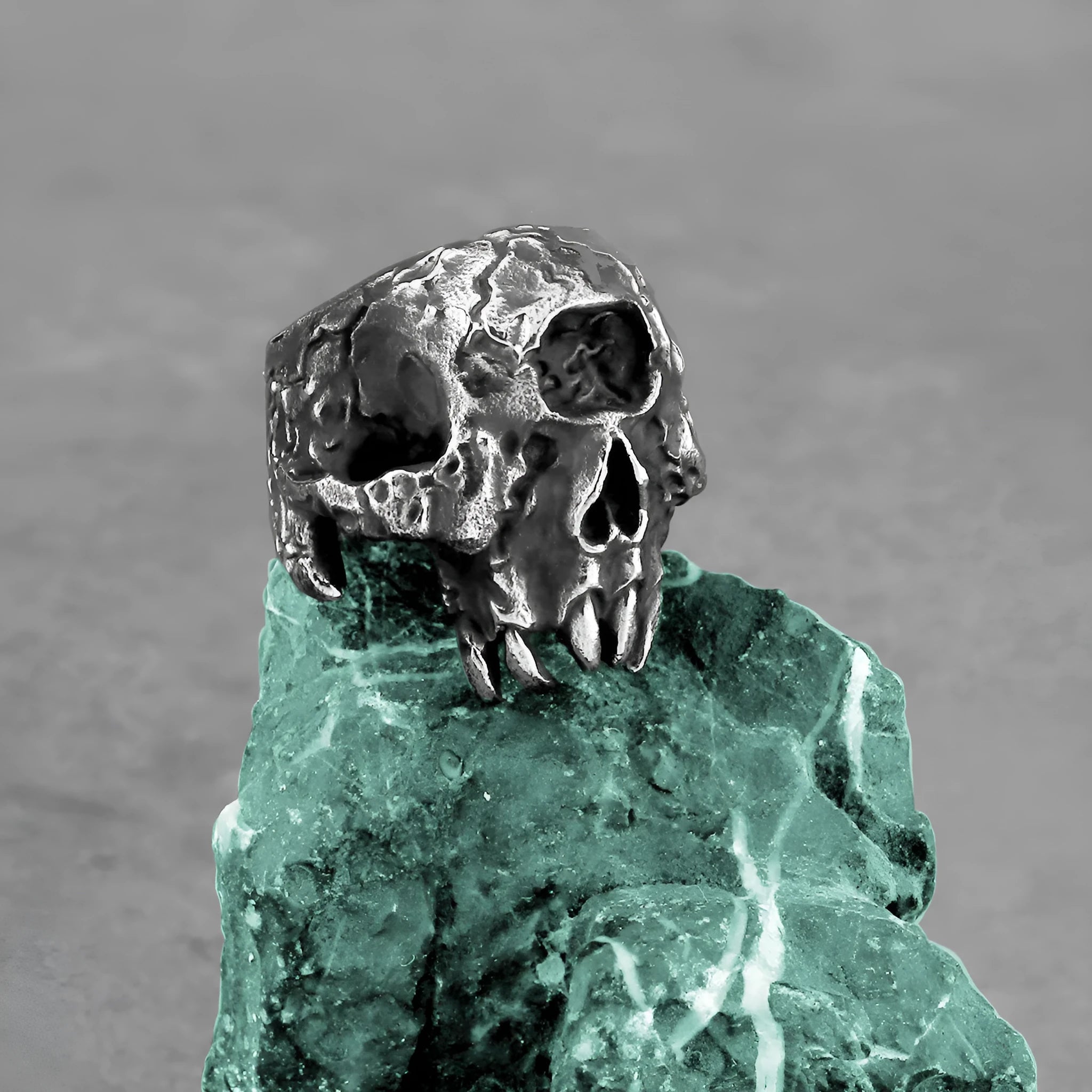 Silver-toned alloy ring with a detailed one-eyed skull design on a black background.