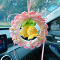 Green woven wool bell orchid floral car pendant hanging from a rear-view mirror.