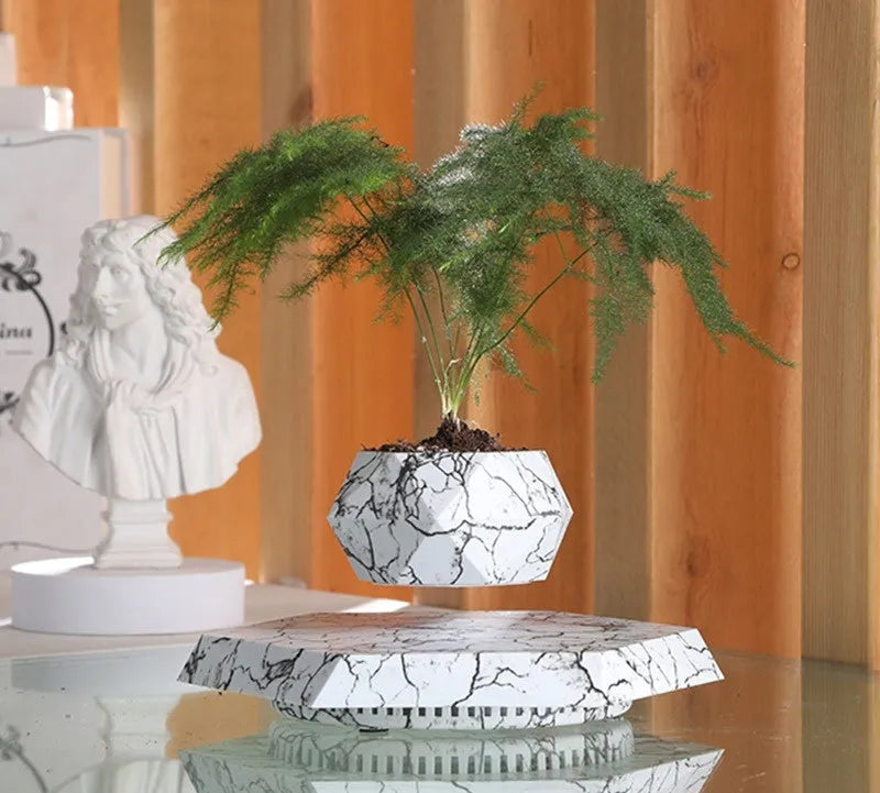 Marble-coloured magnetic levitating plant pot floating above surface with small plant