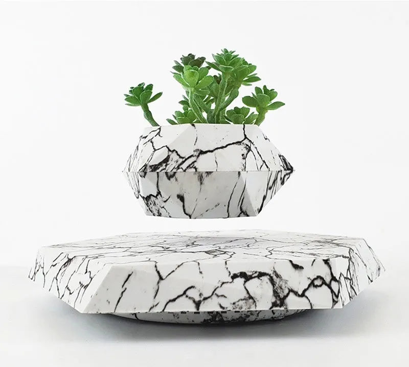 Marble-coloured magnetic levitating plant pot floating above surface with small plant