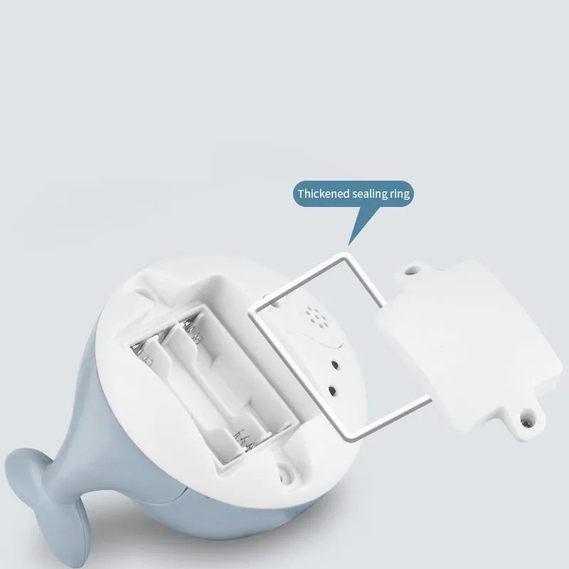 Whale-shaped electric bath toy spraying water with coloured LED lights, shown with base unit on blue background