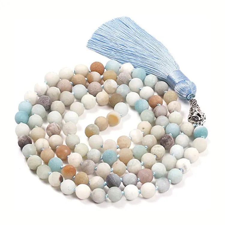 Long blue patterned agate and stone tassel necklace with geometric beads on a white background.