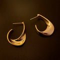 Geometric metal earrings with twisted design and round elements in gold electroplated finish