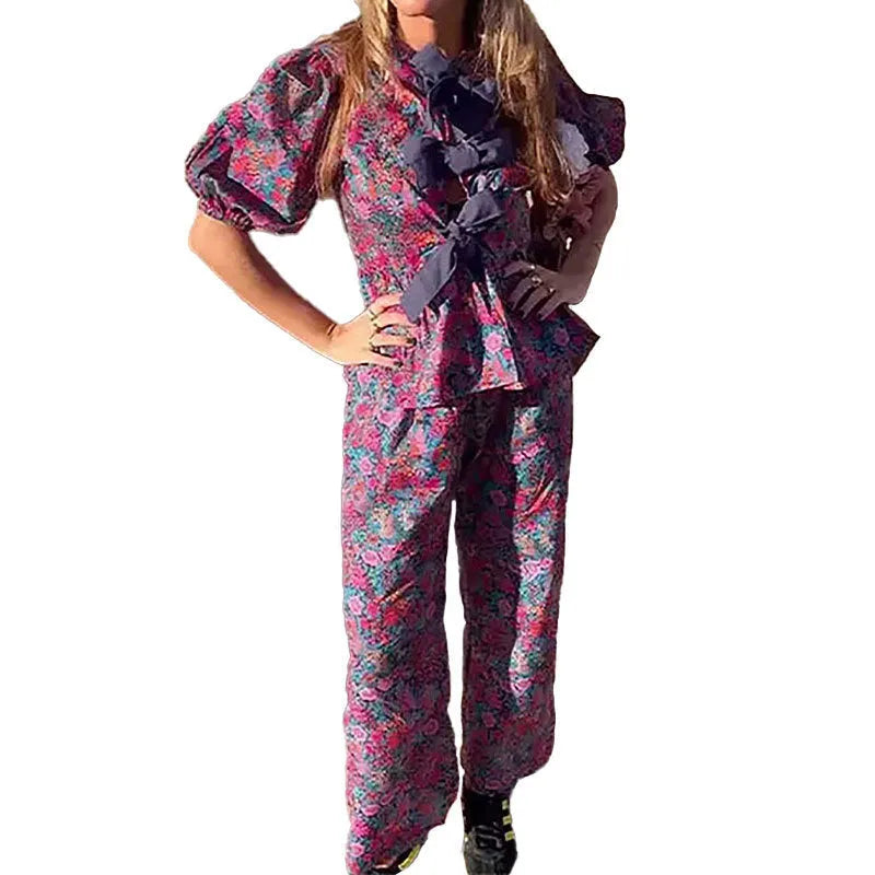 Women's floral print trouser suit set featuring a tie-neck blouse with puff sleeves and matching trousers.