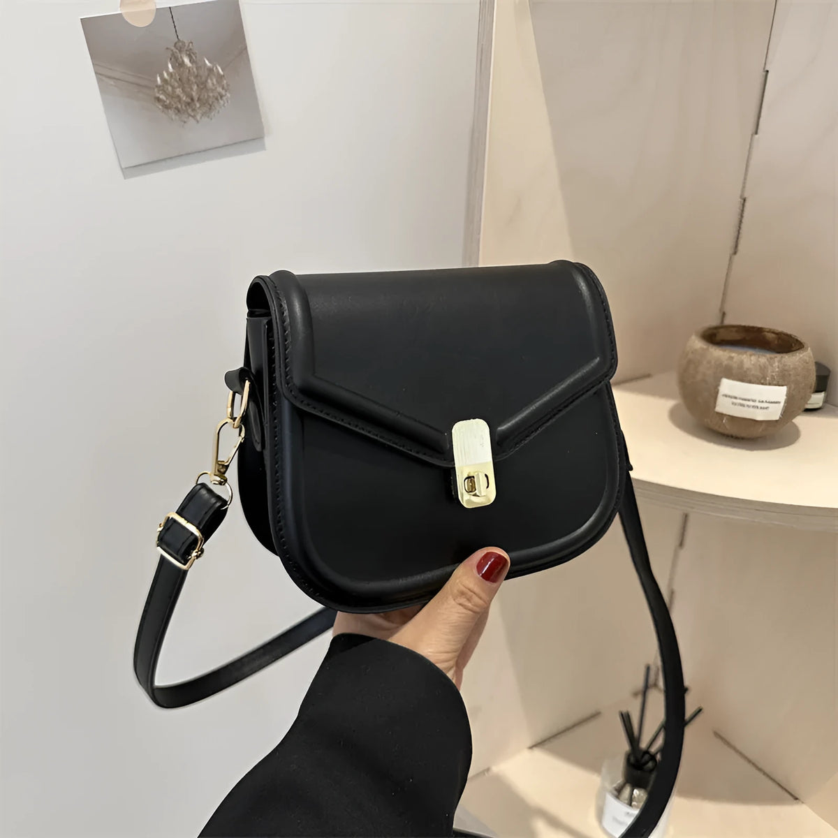 Men's soft black PU leather clamshell messenger bag in a horizontal square shape on a table.