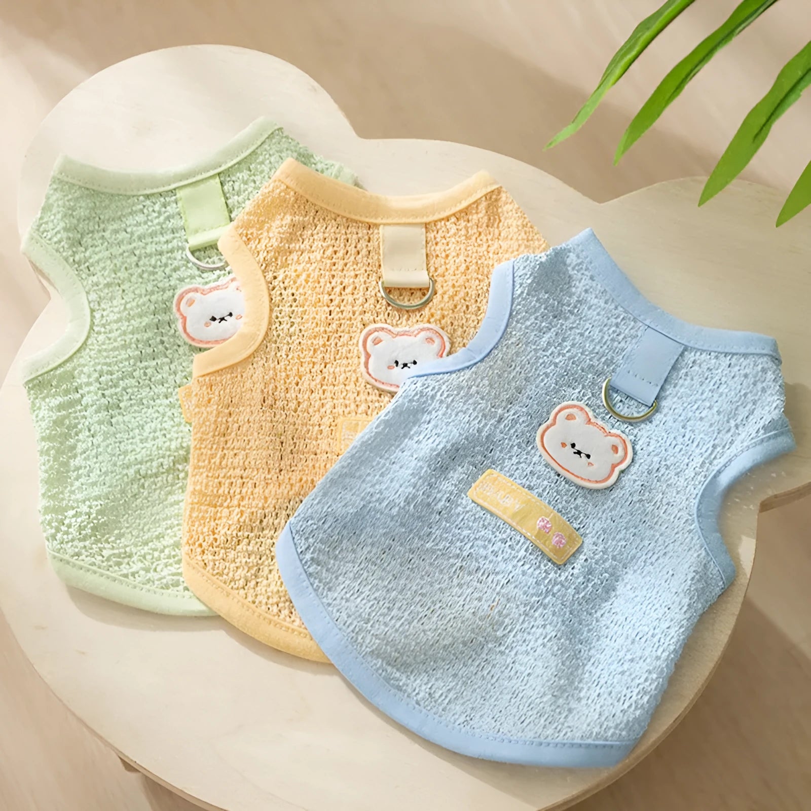 Blue knitted cat clothing with hollowed-out sections and a cartoon bear patch on the front.