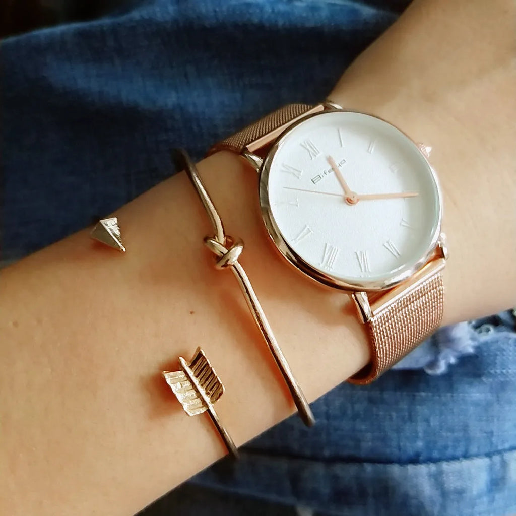 Gold electroplated alloy women's vintage cuff bracelet with knotted arrow design on a white background.