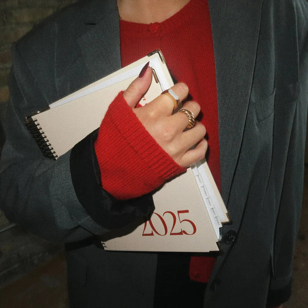 Cherry red coil-bound daily schedule notebook with spiral binding open on a desk