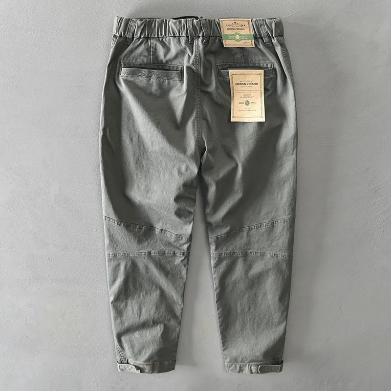 Men's loose-fit khaki cotton overalls with a mid waist and elastic fabric, shown laid flat.