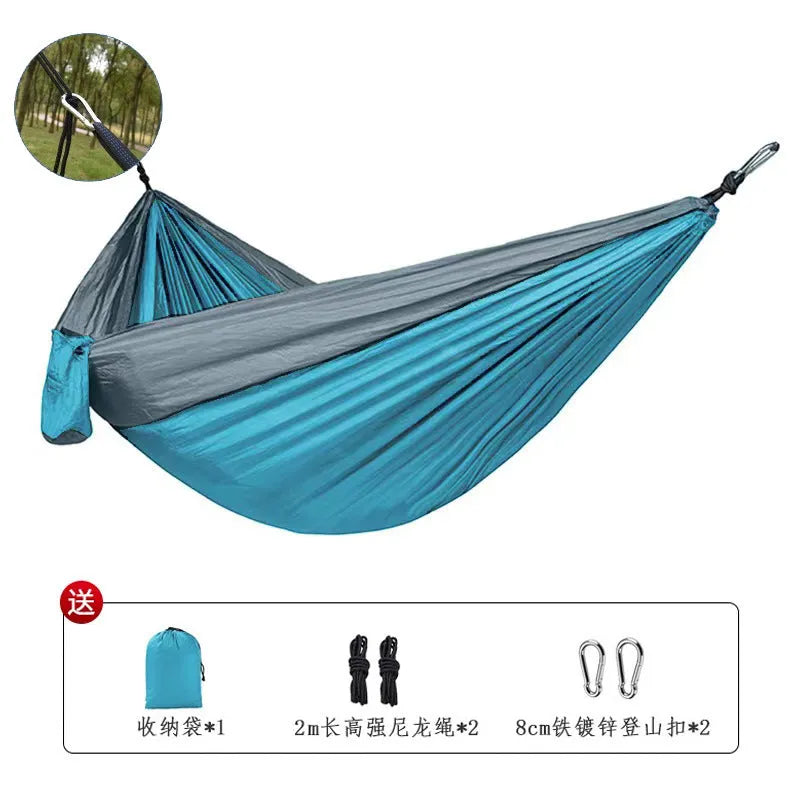 Blue outdoor camping hammock made from parachute nylon fabric, hanging between two trees.