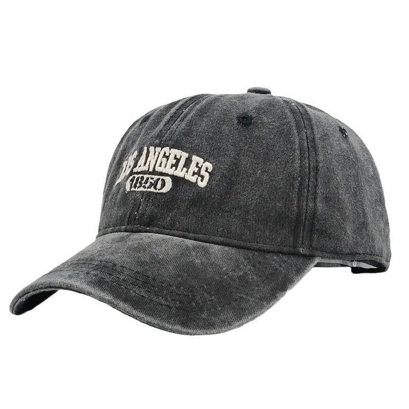 Retro style peaked cap with embroidered distressed letters on the front, shown in beige colour.