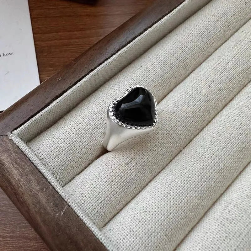 Sterling silver adjustable ring with black agate heart design on model's hand