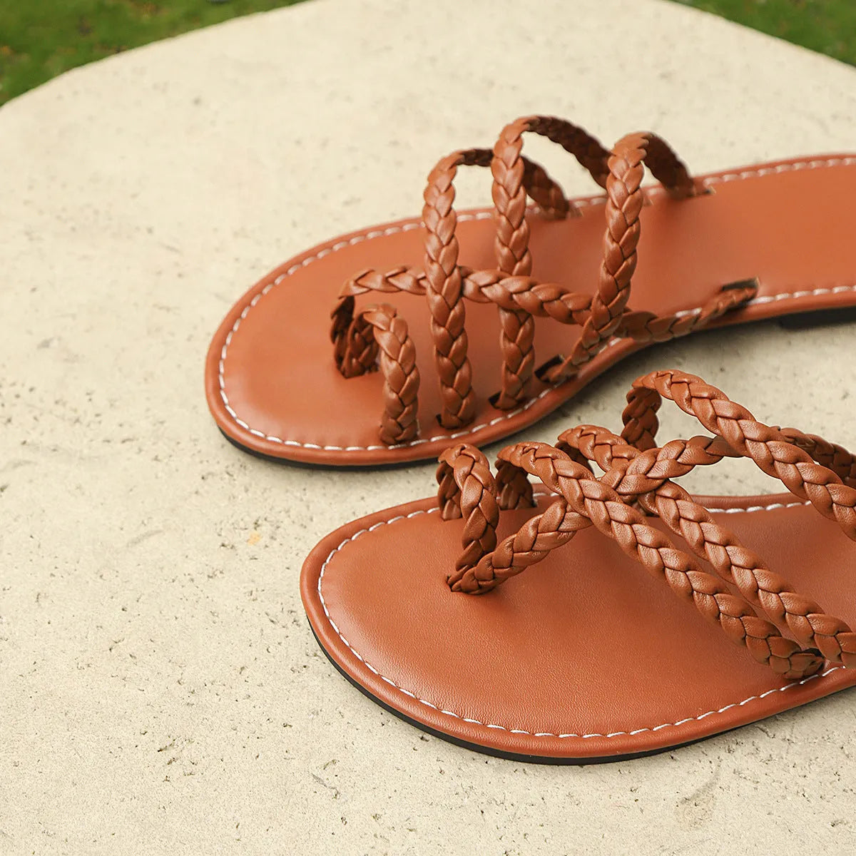 Women's woven clip-toe flat sandals in white, shown on a foot.