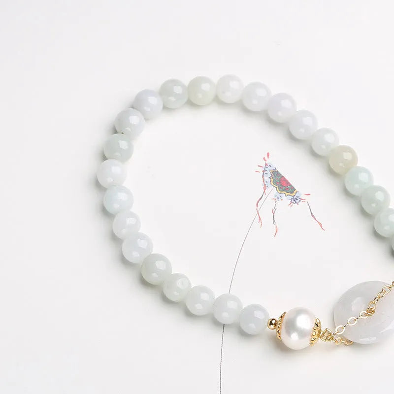 Natural emerald jade bracelet with pearl elements and peace buckle charm on adjustable cord