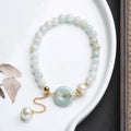 Natural emerald jade bracelet with pearl elements and peace buckle charm on adjustable cord