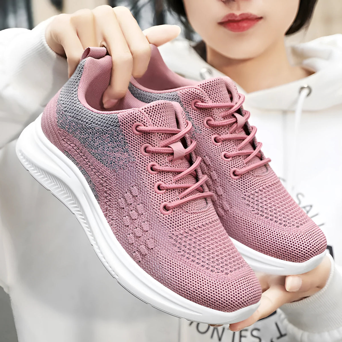 Women's low-top black mesh sneakers with white laces and a round toe on a grey background.