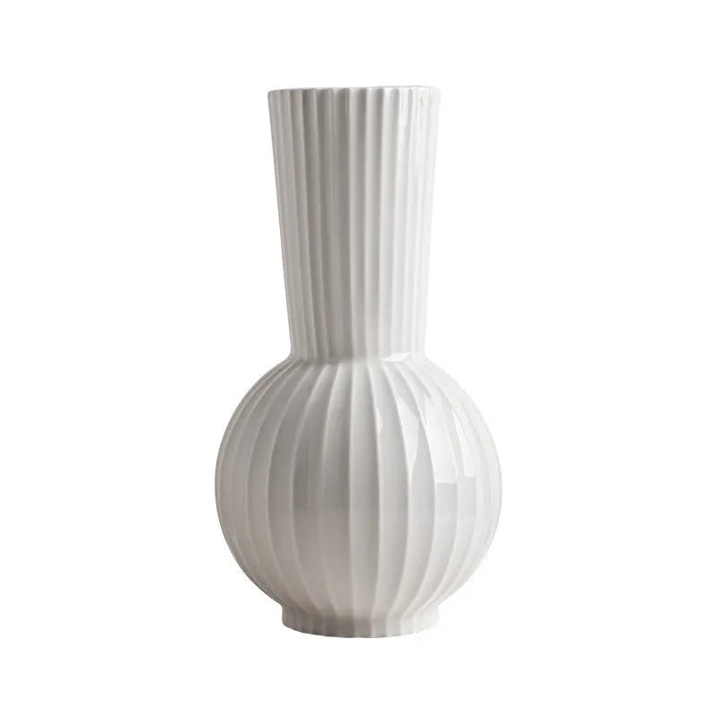 White ceramic ball vase with blue stripes and artificial orchid stems on wooden table.
