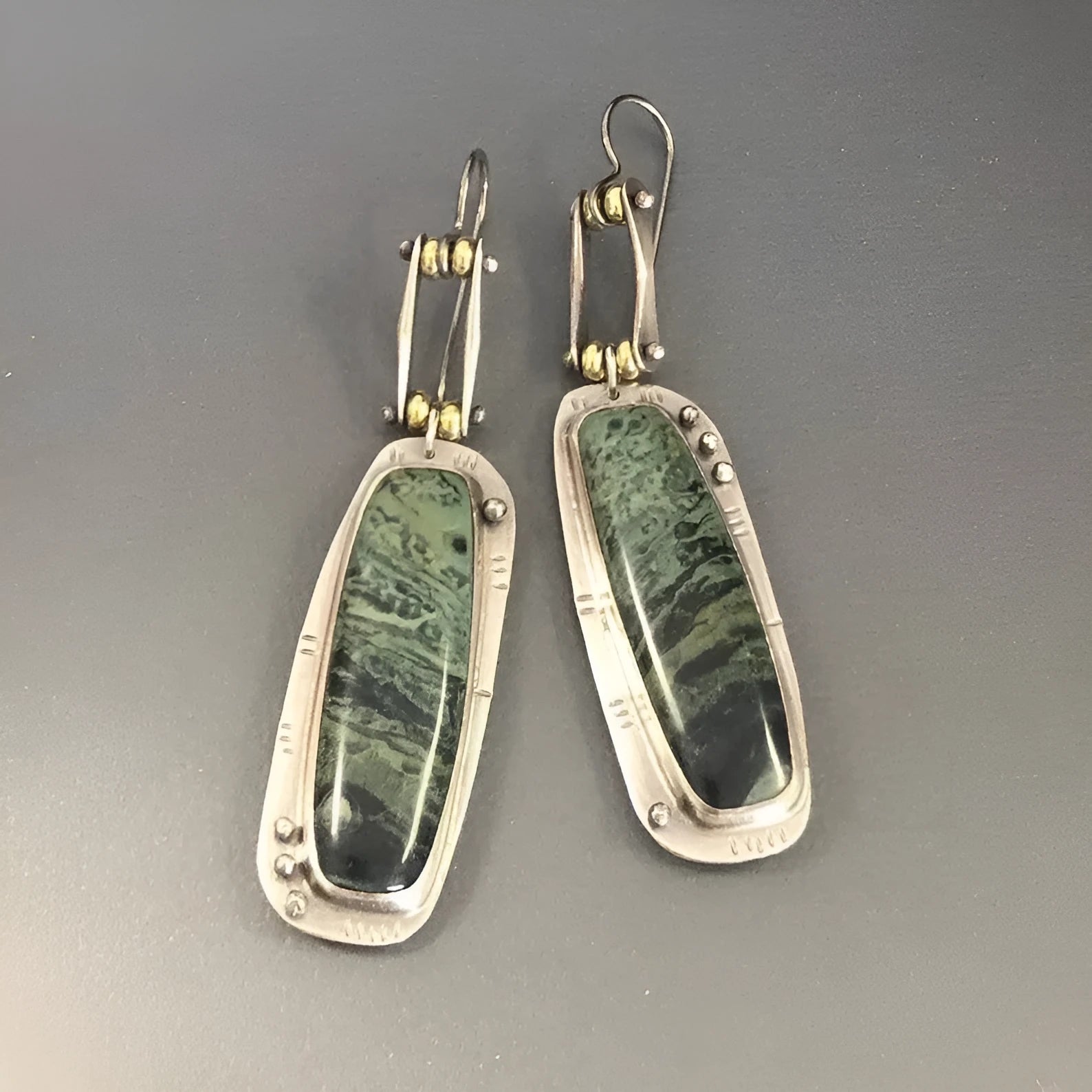 Close-up of simple geometric drop earrings with a two-colour marble pattern finish.