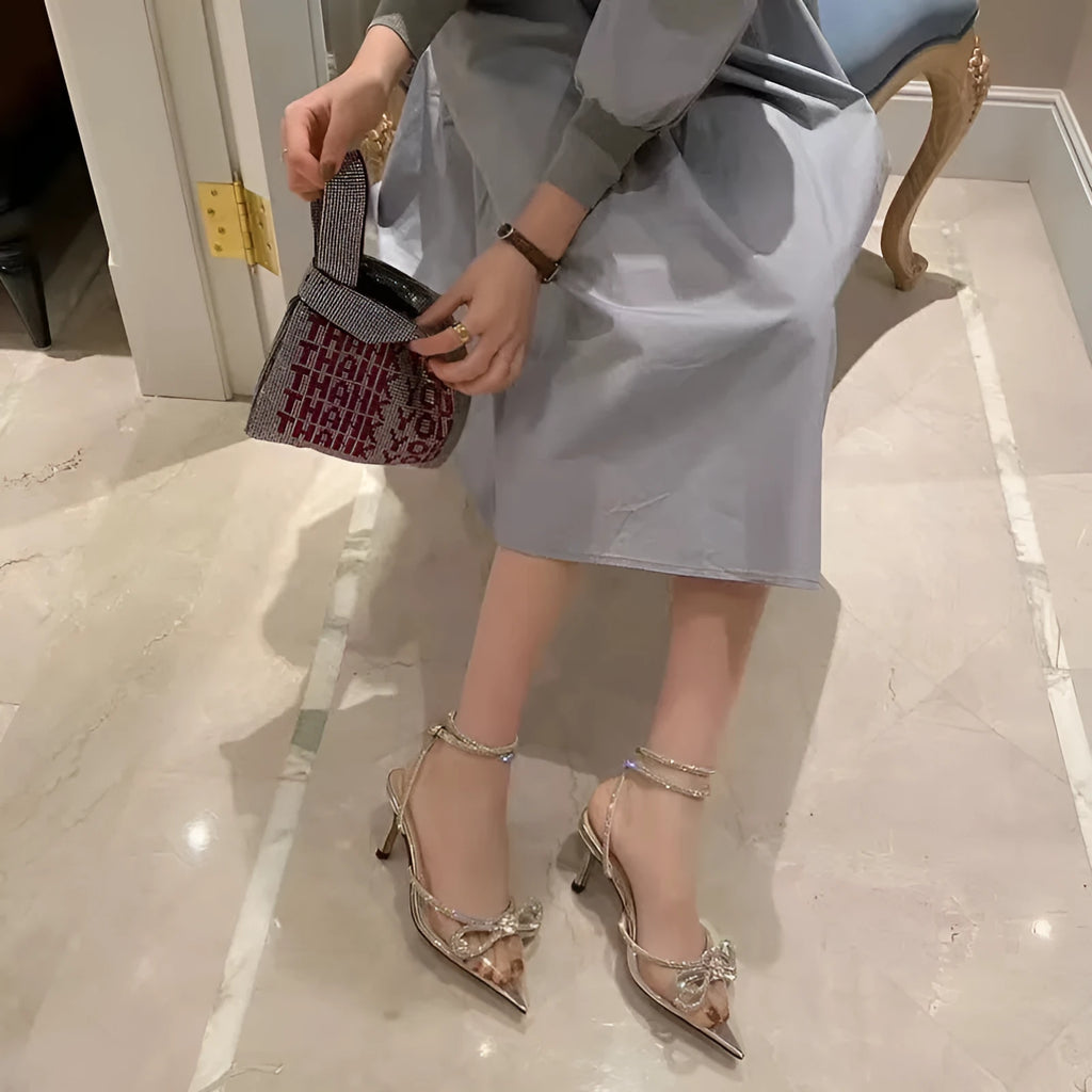 Women's black stiletto heel sandals with a silk bandage strap and buckle fastening on a pointed toe.