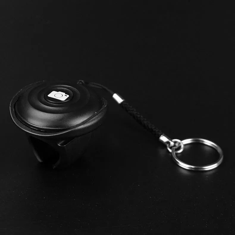 Small black Bluetooth remote control for wireless smartphone camera shutter release.