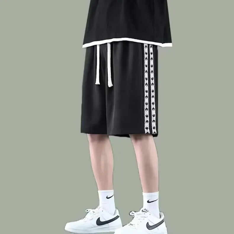 Men's loose-fit black track pants with an elasticated waist, shown on a hanger.