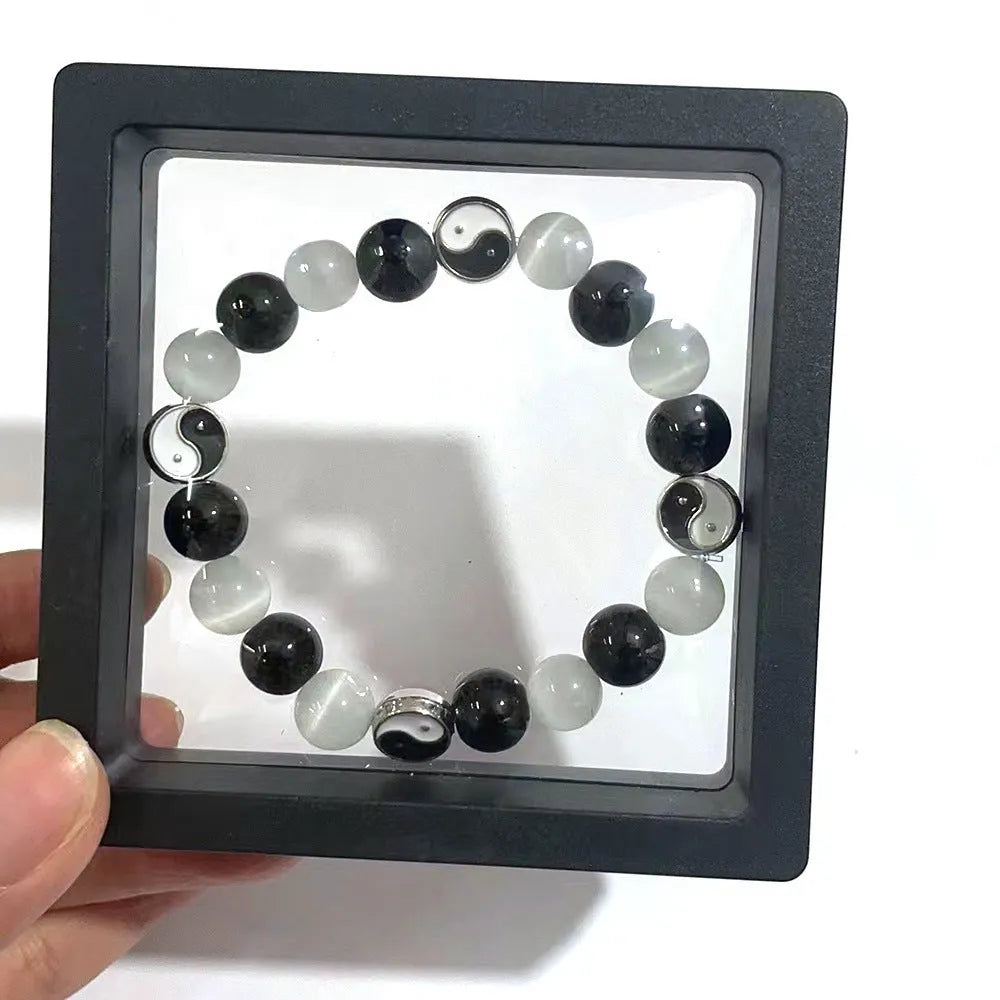 Opal and black agate Tai Chi bracelet with 10mm polished stone beads on a wrist.